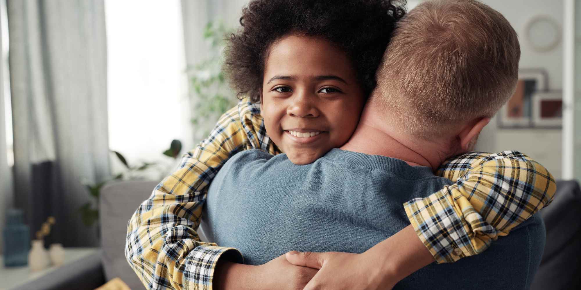 Boy and man in an embrace. What is the difference between fostering and adoption