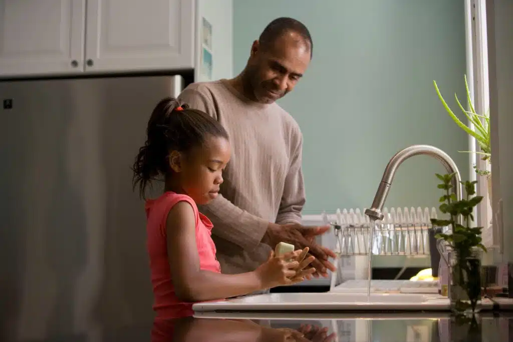 A child washing up with a male adult helping.